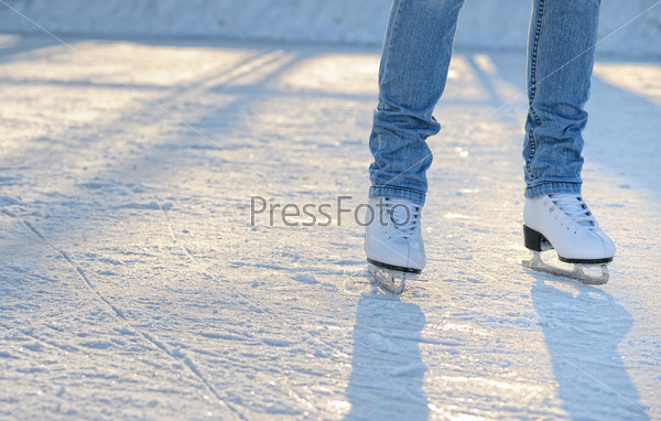 skater\'s legs standing on winter ice rink