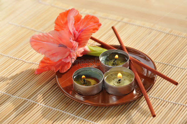 scened  burn candles with flower and incense stick on ceramic plate