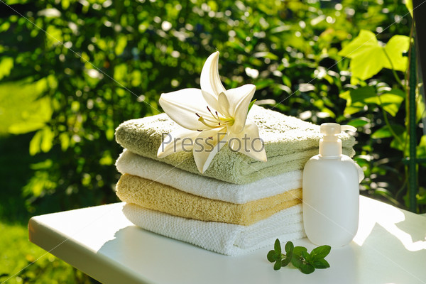 backlighting with sun white lily on stack of towels against green summer background