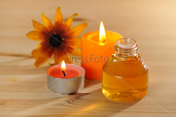 burn scented candles  with brown bottle with essential oil on wood background