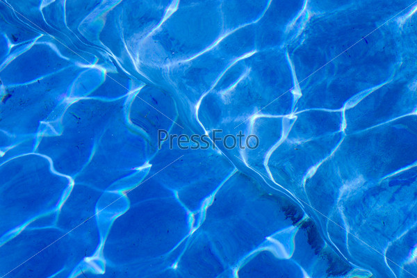 Dirty bottom of the pool under transparent blue water with reflections of sunlight