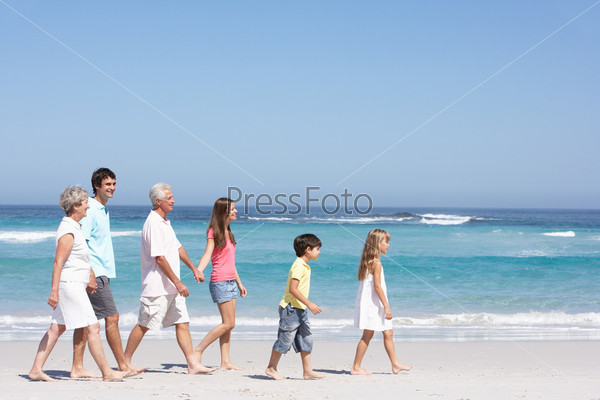 Three Generation Family Walking Along Sandy Beach