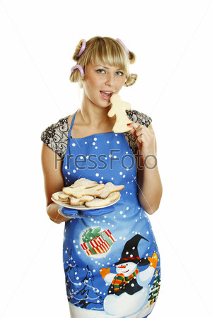 Pretty young woman in an apron and oven gloves holding a plate of gingerbread cookies for the little people christmas