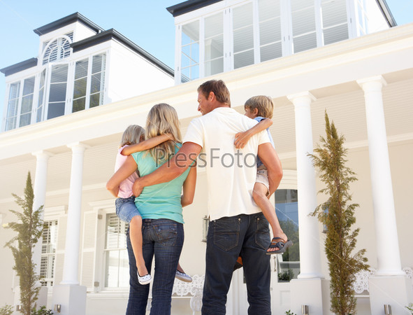 Молодая семья возле красивого дома