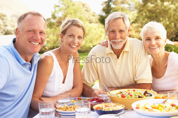 Adult Son And Daughter Enjoying Meal In Garden