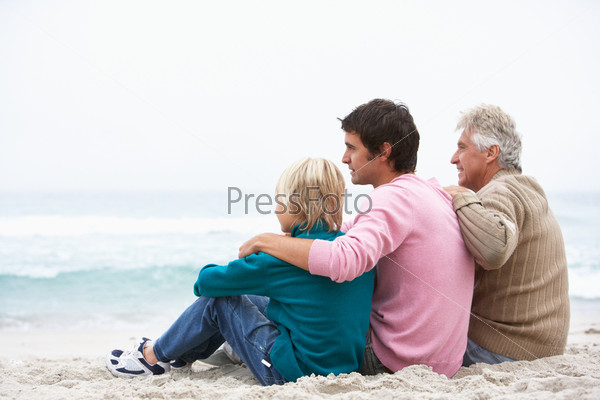 Grandfather, Father And Grandson Sitting On Winter Beach