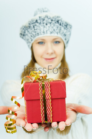 girl in winter hat gives gift box. Studio photography