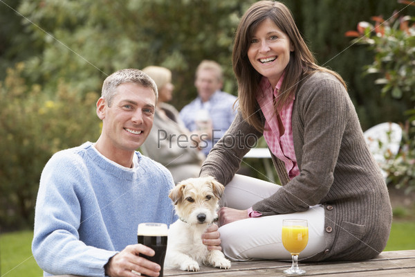 Couple With Pet Dog Outdoors Enjoying Drink In Pub\
Garden