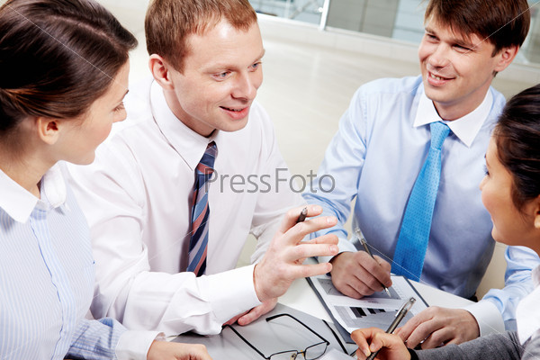 Image of confident businessman explaining something to employees at meeting