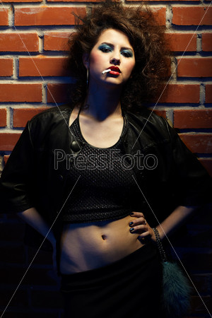 portrait of girl dressed like hooker posing near brick wall