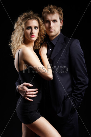 portrait of well-dressed blonde couple on black.