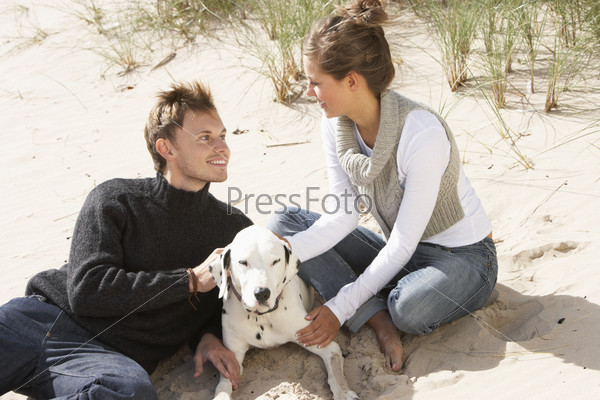 Portrait Of Romantic Teenage Couple On Beach With Dog