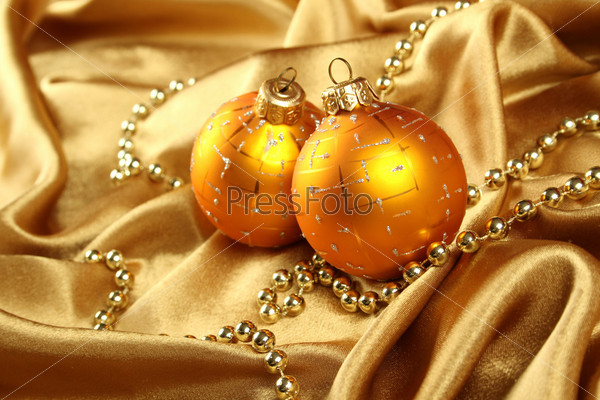 On gold fabric are gold ornaments and Christmas balls of yellow. Background