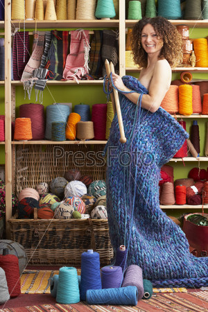 Naked Woman Standing In Knitted Item Standing In Front Of Yarn Display
