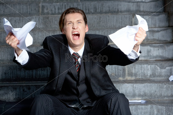 Image of angry businessman with papers in hands raising its