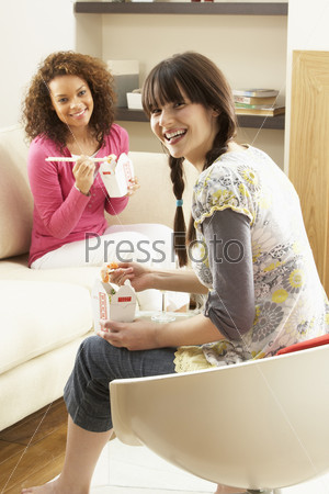 Two Female Friends Enjoying Chinese Takeaway Meal At Home