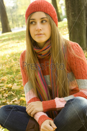 Portrait of a beautiful young woman. Sitting outside in a pile of autumn leaves, smiling