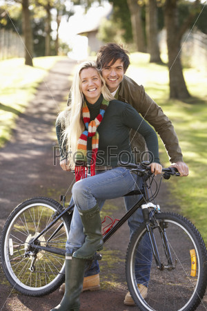 Portrait Of Young Couple With Cycle In Autumn Park