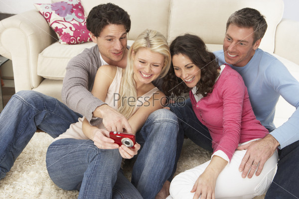 Group Of  Friends Looking At Pictures On Digital Camera At Home
