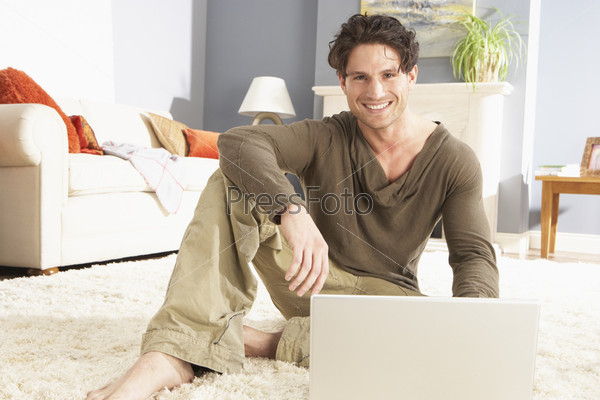 Man Using Laptop Relaxing Laying On Rug At Home