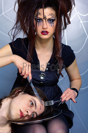 portrait of girl with spider bodyart of face zone with knife and fork preparing to eat her boy victim