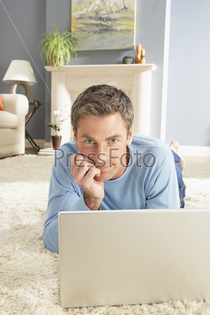 Молодой мужчина с ноутбуком в гостиной