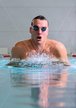 man swims using the breaststroke in indoor pool