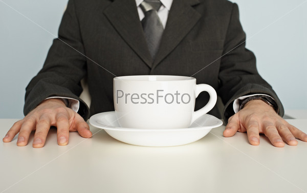 A huge cup of coffee on the table near the businessman, stock photo