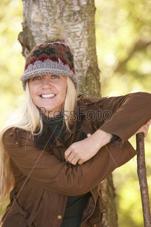 Young Woman Outdoors Walking In Autumn Woodland Holding Walking Stick