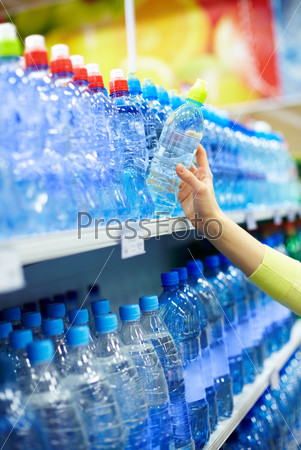 Close-up of female holding plastic bottle of mineral water in a shop