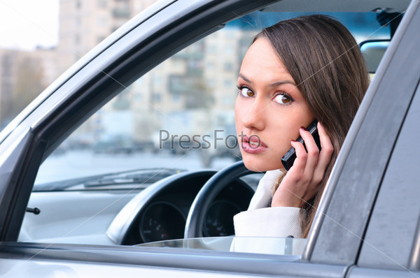 Sensual young woman is talking phone in car