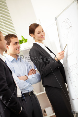 A businesswoman showing a scheme on a whiteboard to her colleagues
