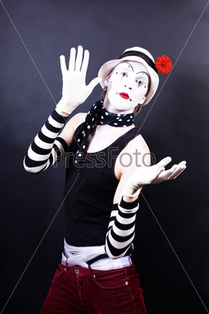 Theatrical mime in white hat with red flower on black background, stock photo