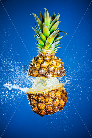 Pineapple splashed with water on a blue background