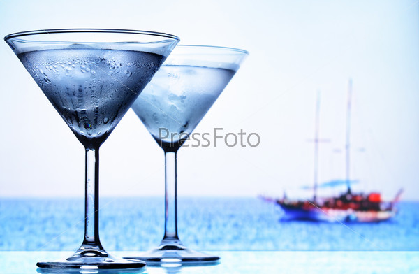 Two cocktail glasses and sea in the background