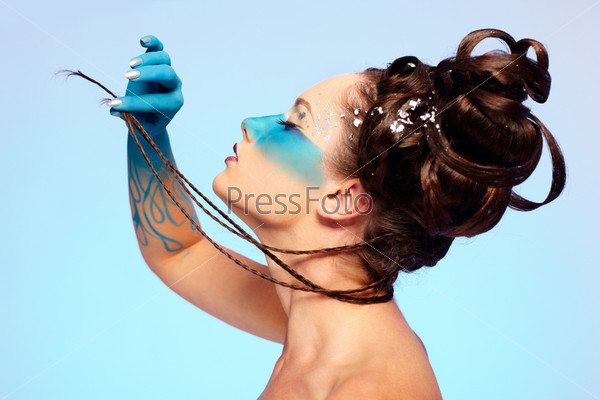 portrait of beautiful girl with blue stripe facial bodyart and fantasy hair-do pilling her several thin long braids