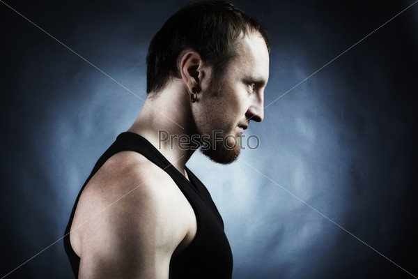 Strong athletic man on black background. Shooting in studio, stock photo