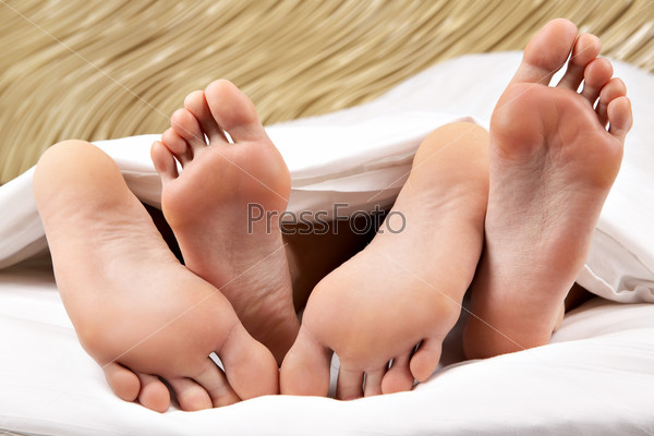 Image of two pairs of bare male and female feet during sleep