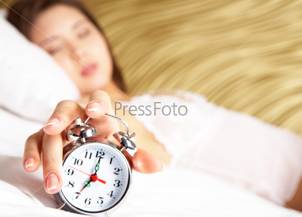Image of female hand on top of alarm clock after awakening in the morning