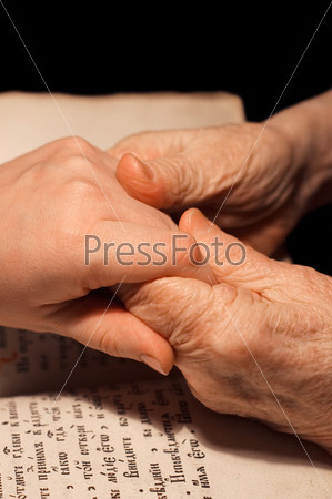 Old and young hands on the bible