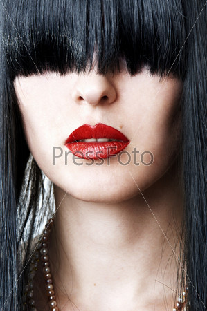 closeup fashion portrait of glamour woman face with red lips and creative black hairstyle with bang covering her eyes