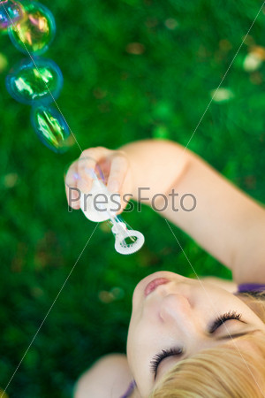 young female makes soap bubbles