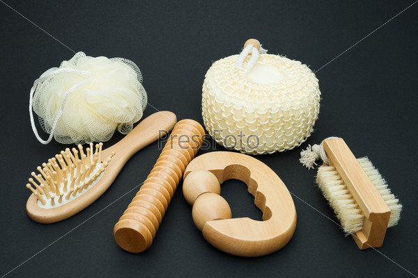 Bath set - massage brush with wooden studs, massage roller, sponge, loofah on a dark background.