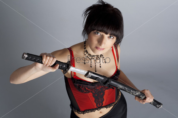 Woman in the studio with samurai sword on grey background