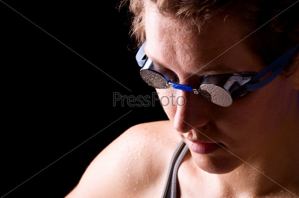 concentrated woman swimmer is looking downstairs on black background