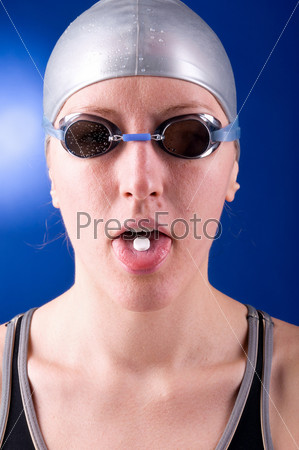 ill woman swimmer is showing a tablet on her tongue