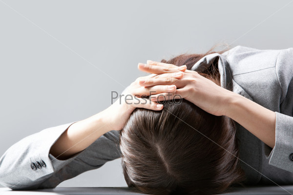 A young woman hiding her face on table, stock photo