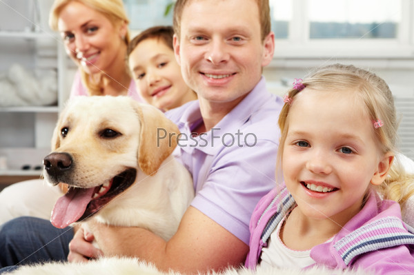 A happy family of four with a dog sitting on sofa, the focus is on the daughter , stock photo