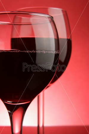 Two glasses of red wine close-up over red background
