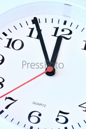 Wall clock dial close-up, five minutes to twelve
